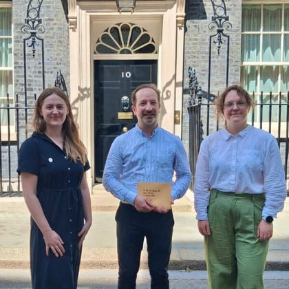 Three people standing outside 10 Downing Street holding a joint letter