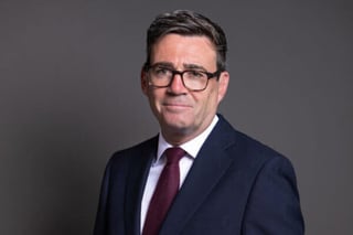 Picture of Andy Burnham in a dark blue suit with a purple tie looking at the camera