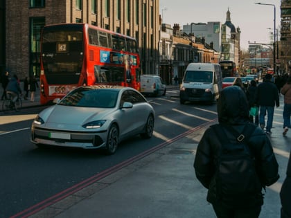 Car being driven down a busy London street with pedestrians, bus and other road users