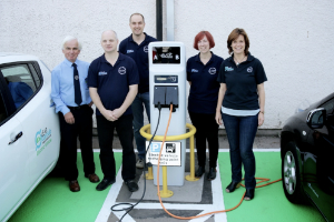 Community car club with members standing around an EV charger