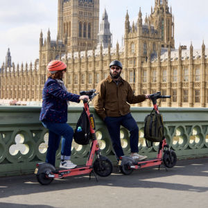 E-scooter riders standing on a bridge in front of the Houses of Parliament