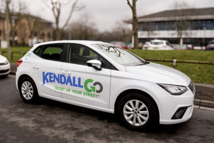 A parked white Kendall Go car with logo on the side