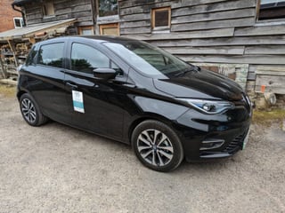 A black Renault Zoe car with Malvern Hills Car Club graphics on the side