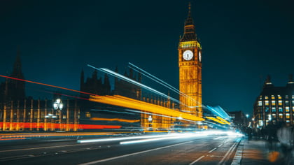 The Houses of Parliament at night with a colourful time lapse of traffic cutting in front of it